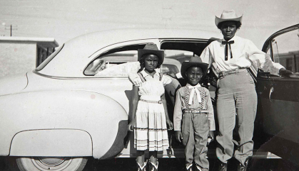 A woman and two children pose in front of a car in this undated photograph.