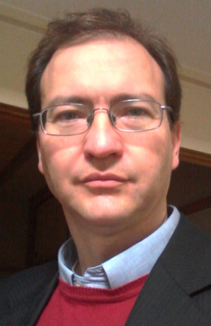 Man wearing red sweater and blue shirt and dark blue jacket.