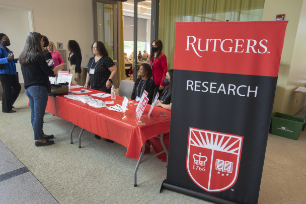 Registration table with staff assisting guests at registration with Rutgers Research banner on the side.