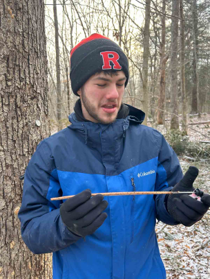 In a forest, Josh Kover holds a tree core sample for Rutgers research.