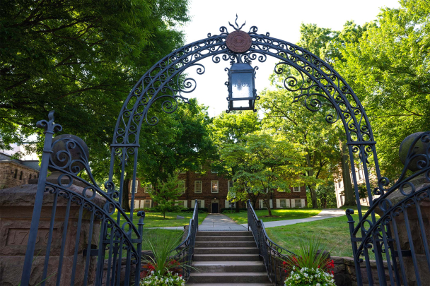 Old Queens, seen through the Class of 1902 Gate, is obscured by lush trees during the summer months.