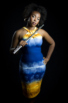 Adrienne Baker in a blue and yellow dress, holding a flute.