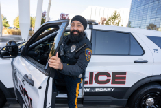 Gurwinder Singh standing next to Rutgers Police Car