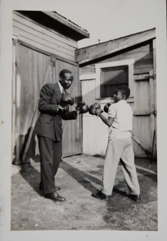 A man and a boy wearing boxing gloves pose for the camera in this undated photo.
